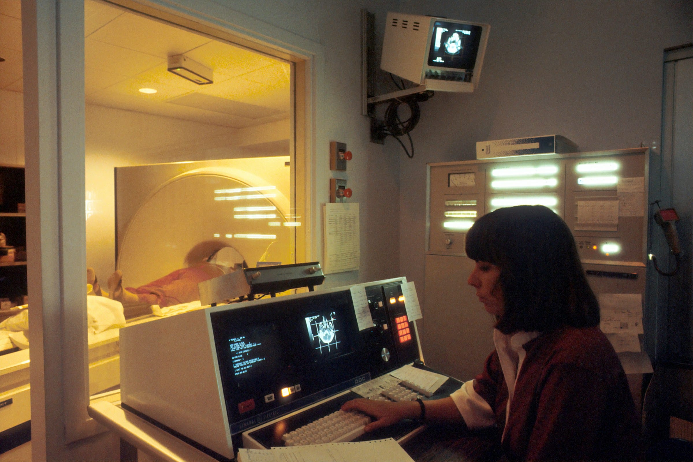 Medical professional operating CT scan equipment with patient in scanner